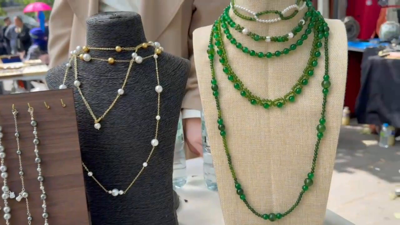 Green and light-coloured beaded necklaces on display busts at the Paris stall.